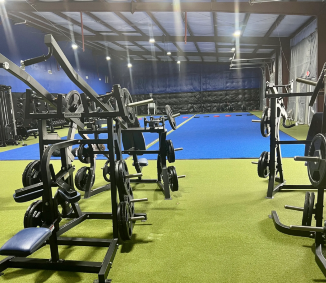 Wide view of two performance turf bays and plate-loaded racks inside Texas Athletics USA Northwest Houston
